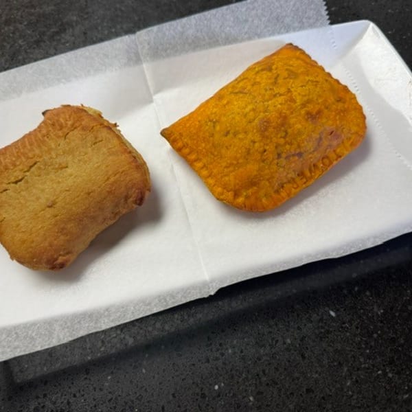 Two pastries, one golden brown and one orange, on white paper in a white tray.