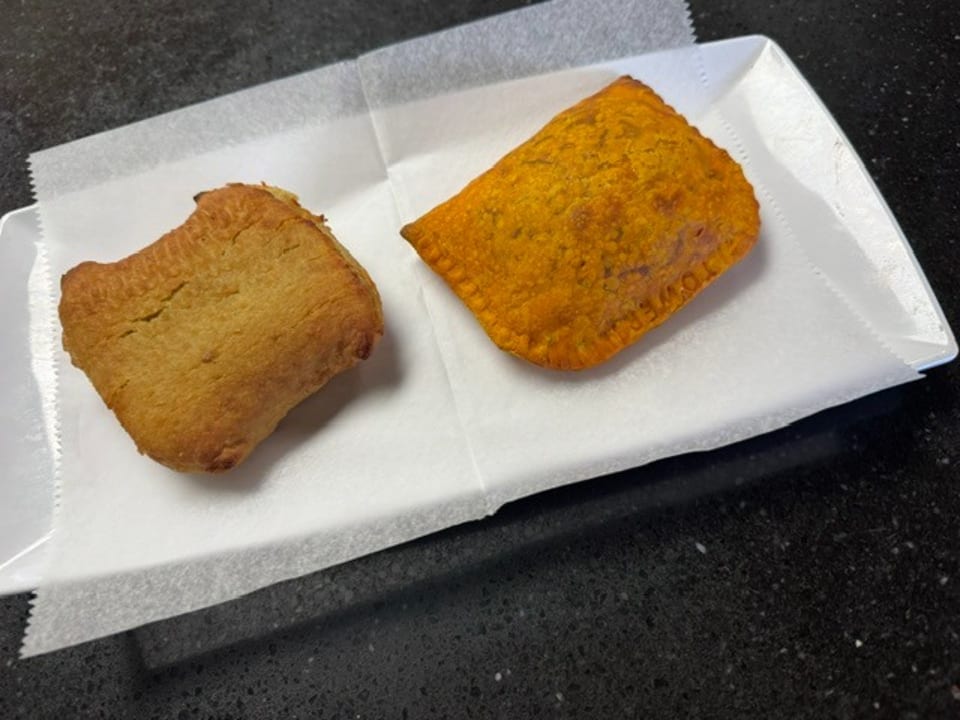 Two pastries, one golden brown and one orange, on white paper in a white tray.
